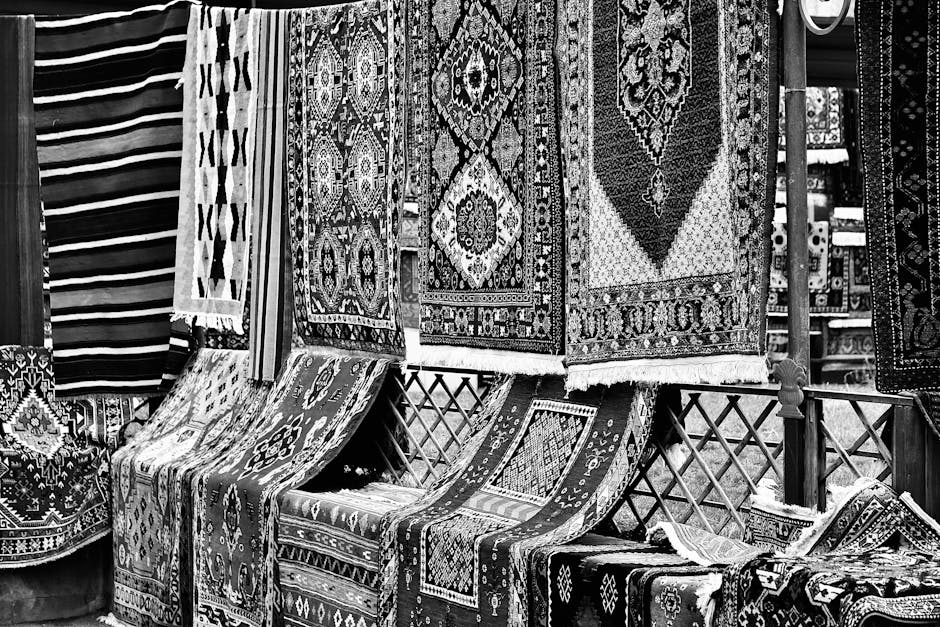 A close-up view of a traditional patterned rug with intricate geometric designs in red, yellow, blue, and white, partially rolled back to reveal the wooden floor beneath. The rug's edges have a fringe detail. Bright natural light illuminating the scene highlights the cleanliness and condition of the rug, indicating recent professional cleaning by Twickenham Carpet Cleaning. The surrounding area features a smooth, polished wooden floor, free of dust or debris, in a residential room setting. This image emphasizes surface cleaning and deep cleaning services offered by Twickenham Carpet Cleaning for domestic spaces.